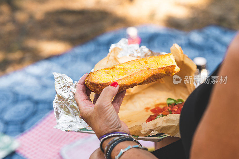 老年妇女在野餐时吃自制的意式烤面包