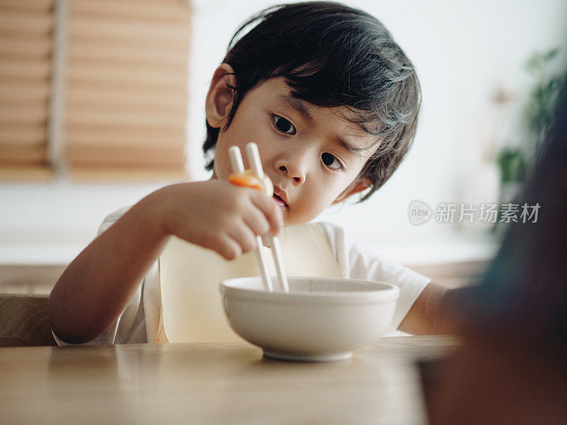 微笑的小男孩在高椅子上吃