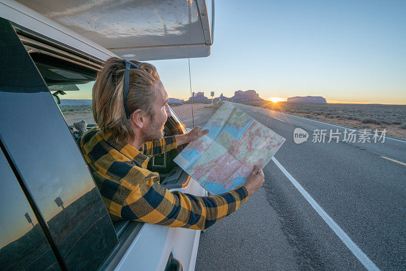 公路旅行概念;一个年轻人在帐篷里看地图寻找方向，探索国家公园和自然，准备冒险。