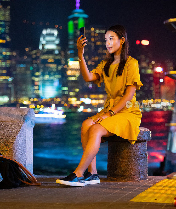 女士和香港著名城市景观地标景观，用手机自拍