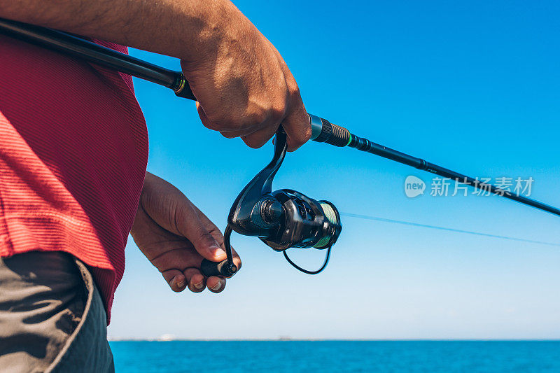 夏天，渔夫在海边钓鱼时，站着扔钓竿。