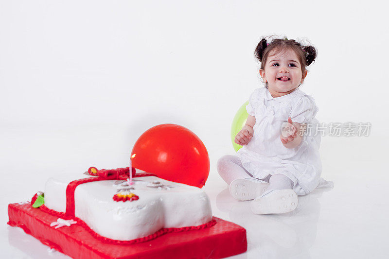 小女孩坐在生日蛋糕旁边