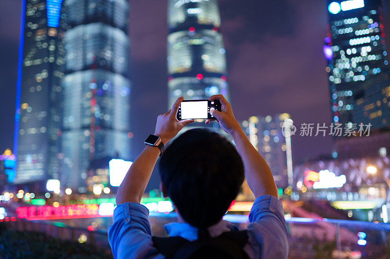 年轻的亚洲男子用智能手机拍照