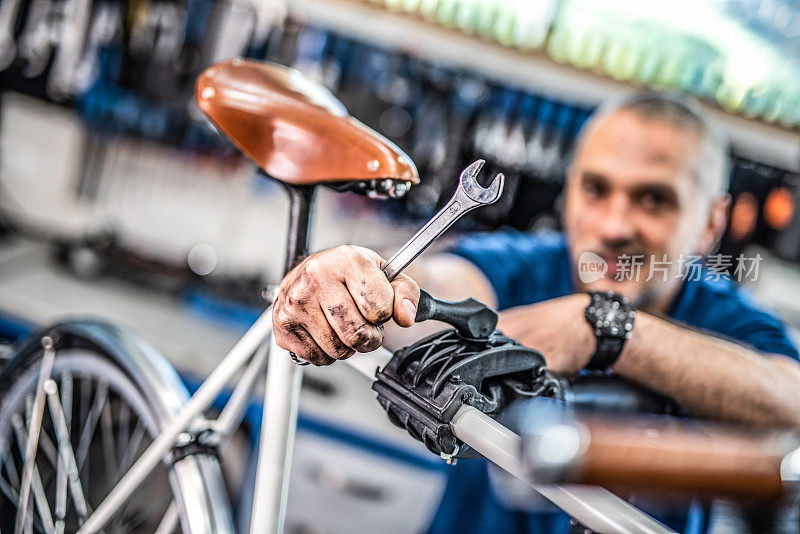 自行车修理工在自行车车间里拿着一把扳手。
