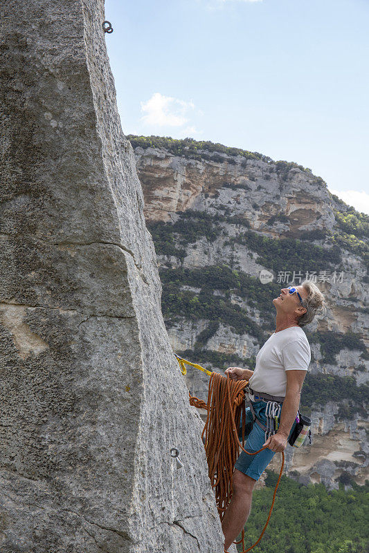 攀岩者从岩石尖顶探出身子，计划下一步行动