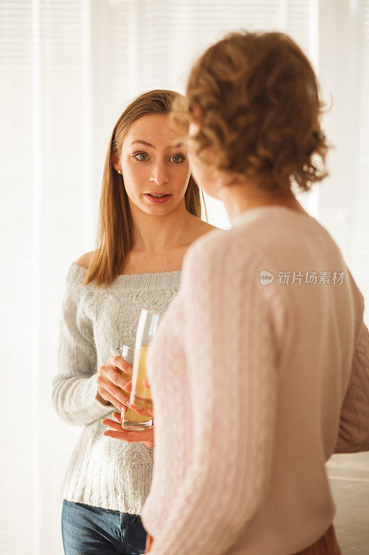 年轻女子一边喝着柠檬水一边和她妈妈聊天