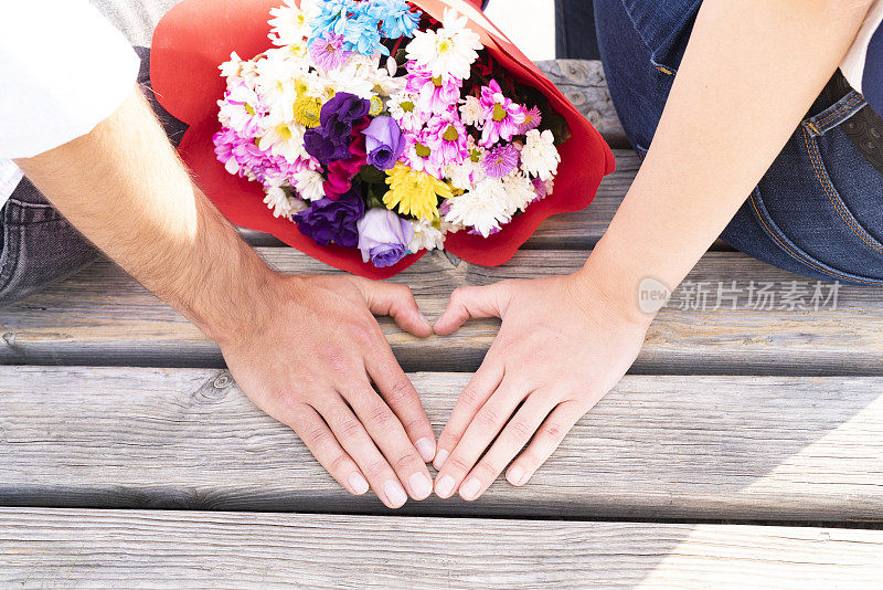 花束和两个恋人的手。心形手