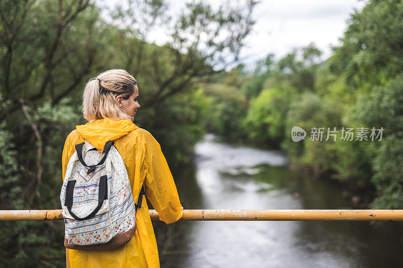 桥上穿着雨衣微笑的女人享受着大自然