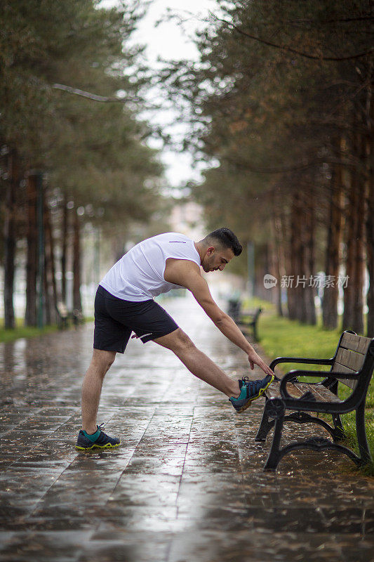 年轻人在雨中伸腿。