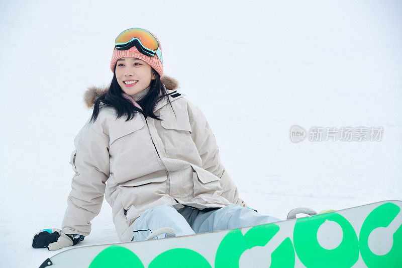 踩着单板坐在雪地上的青年女人
