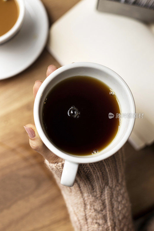 咖啡杯，女士的手拿着咖啡杯，女士拿着一个白色的杯子