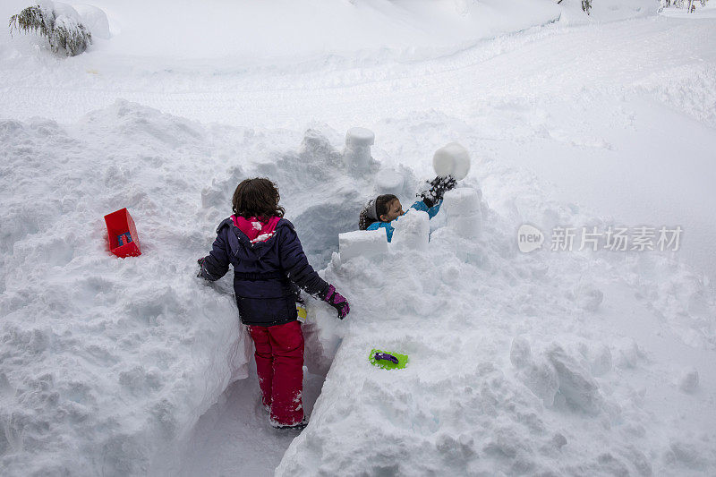 年轻的女孩们在厚厚的积雪中建造雪堡