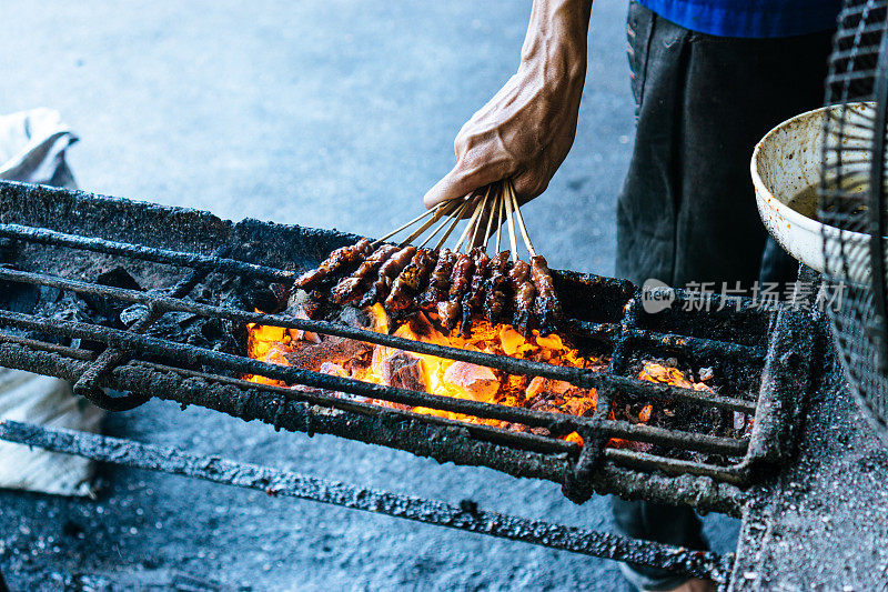 人们在燃烧的木炭上烤鸡肉