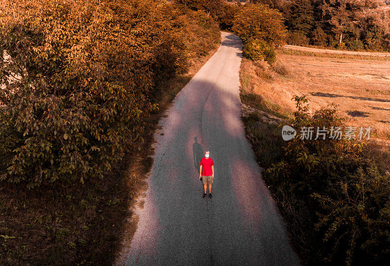 戴着口罩的男子独自走在乡村小路上