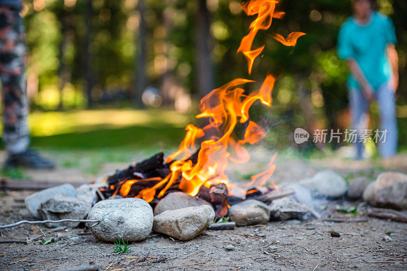 夜晚燃烧森林。在山中户外的旅游营地里营火。火焰和火焰火花在黑暗的抽象背景。我们正在准备户外烧烤。地狱之火。燃料、动力和能源。篝火在森林的水边
