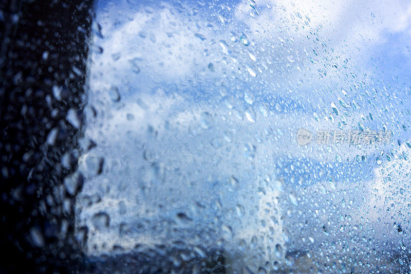 雨点在窗户与蓝色的天空背景。