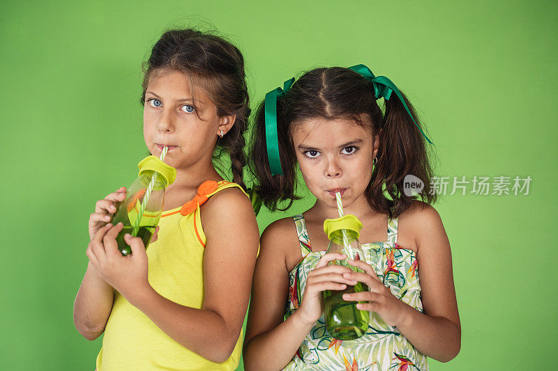 两个女孩用可重复使用的瓶子喝提神饮料
