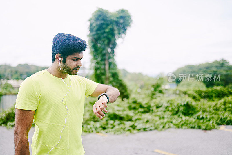 年轻的印度男子在跑步后看智能手表