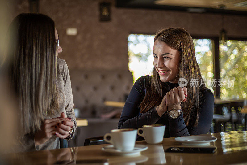 两个开心的女人在咖啡馆里喝咖啡。