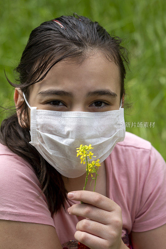 戴着面具的少女闻着一朵花