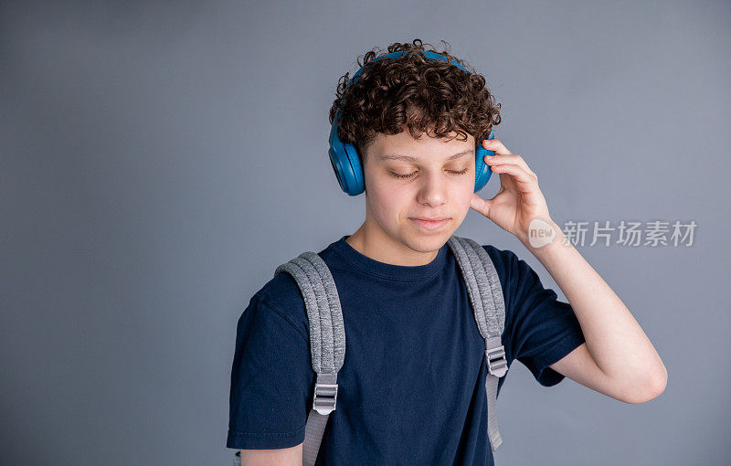 十几岁的男孩是学生，背着背包，戴着耳机