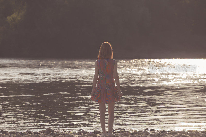 红发瘦弱的女孩站在河边