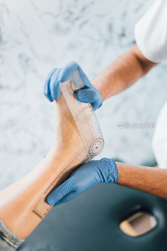 近距离的手足病医生的手与医用手套探索的脚病人在足病诊所。