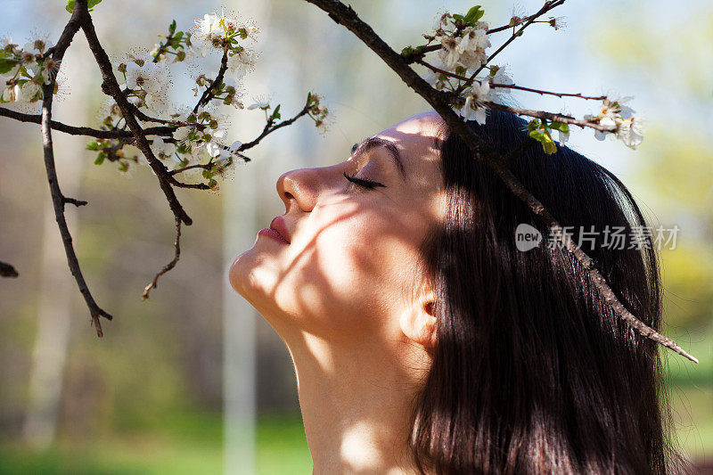 闻着花的美丽年轻女子