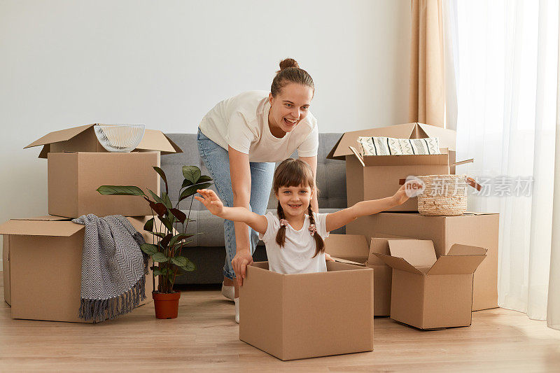 母亲和女儿在新家玩耍，坐在纸板箱里大笑，看起来很饱，情绪很好，搬到了新公寓。