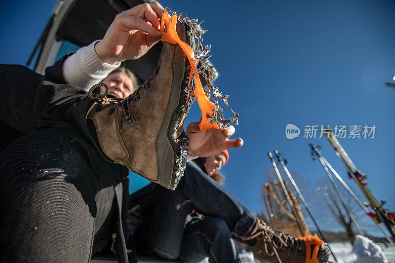 从低角度观看一个男人在他的登山靴上穿冰爪