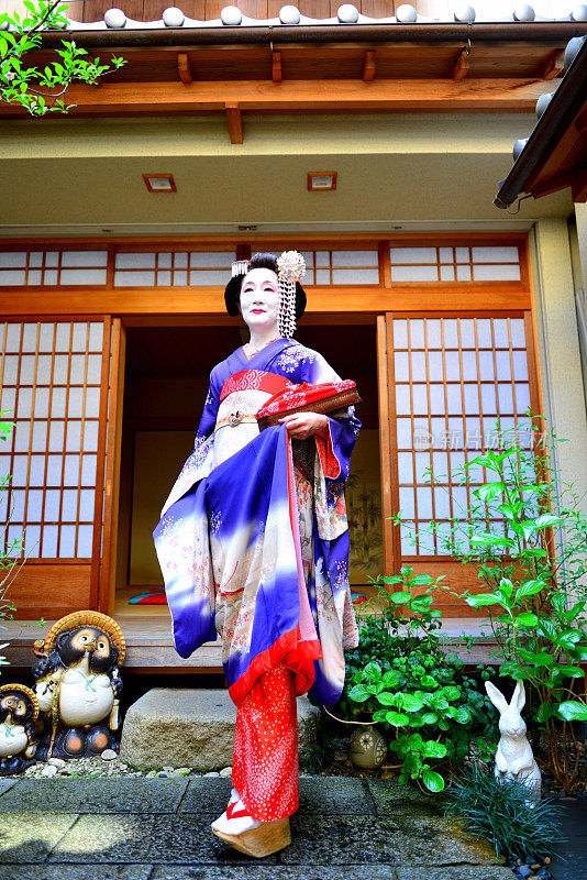 穿着舞妓服装的日本女人站在京都艺妓屋的庭院里