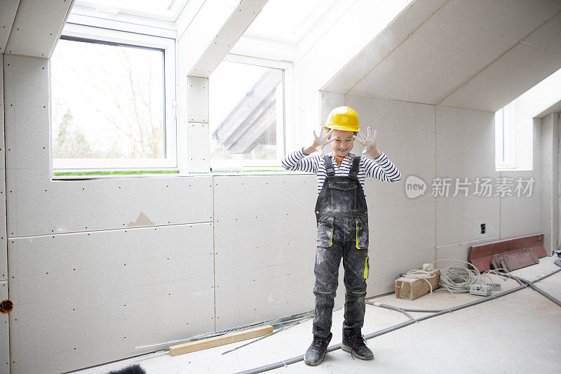 酷酷的小男孩戴着黄色安全帽，在建筑工地摆造型，玩得很开心