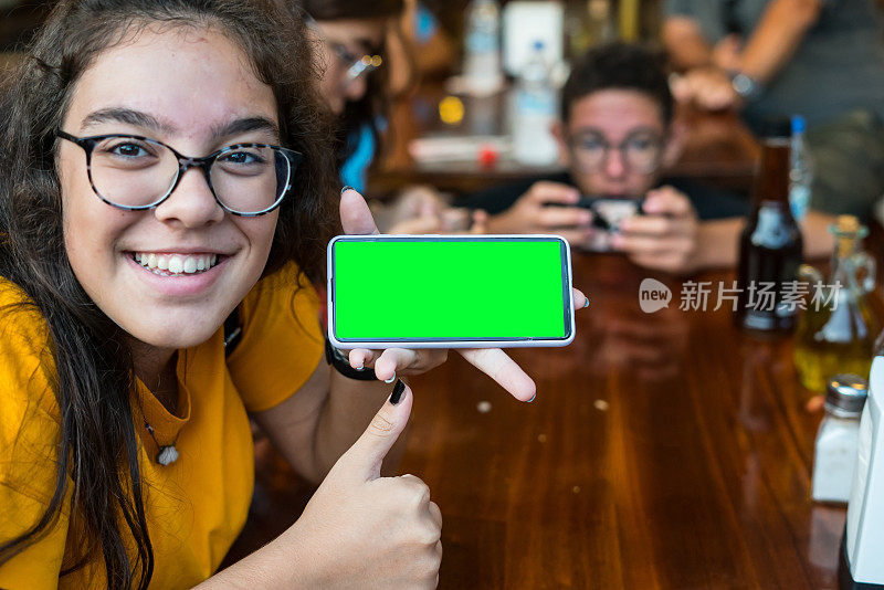 孩子们正在玩手机游戏的背景，一个女孩展示手机的绿色屏幕和女孩做得好水平的照片