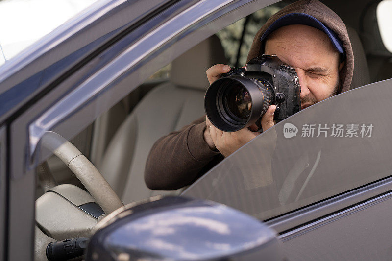 私家侦探坐在车内，用专业单反相机拍照