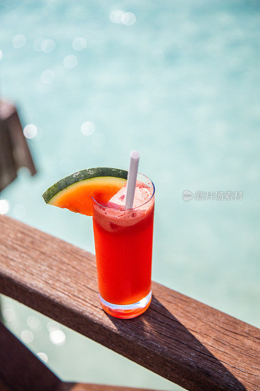 在阳光明媚的日子里，在海边喝新鲜的西瓜汁奶昔