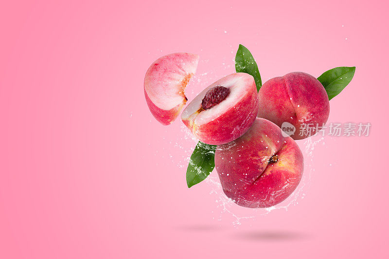 创意布局由整个和切片成熟多汁的桃子，水果和水溅在粉红色的背景