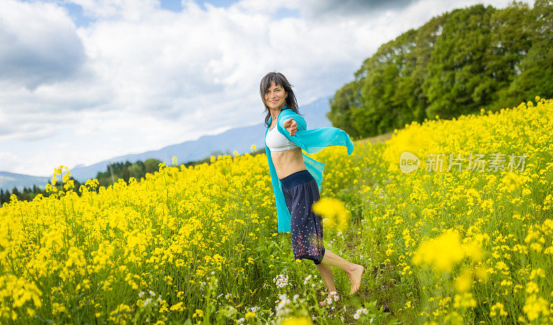 一位妇女在一片黄色的油菜花地里放松和享受户外活动