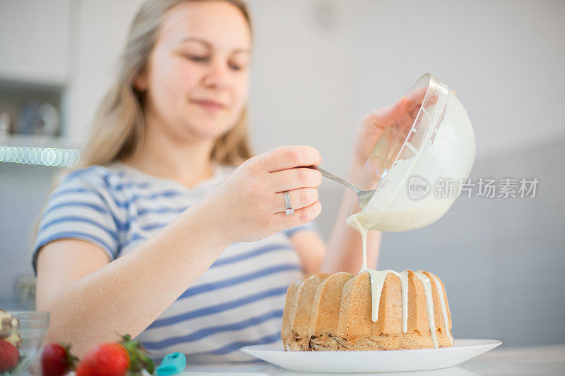 年轻女子正在装饰库格霍夫蛋糕，并把融化的白巧克力倒在上面