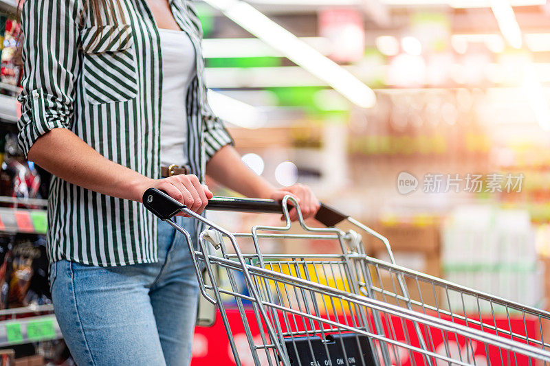 超市里推着购物车的女人。在杂货店买食物。超市购物