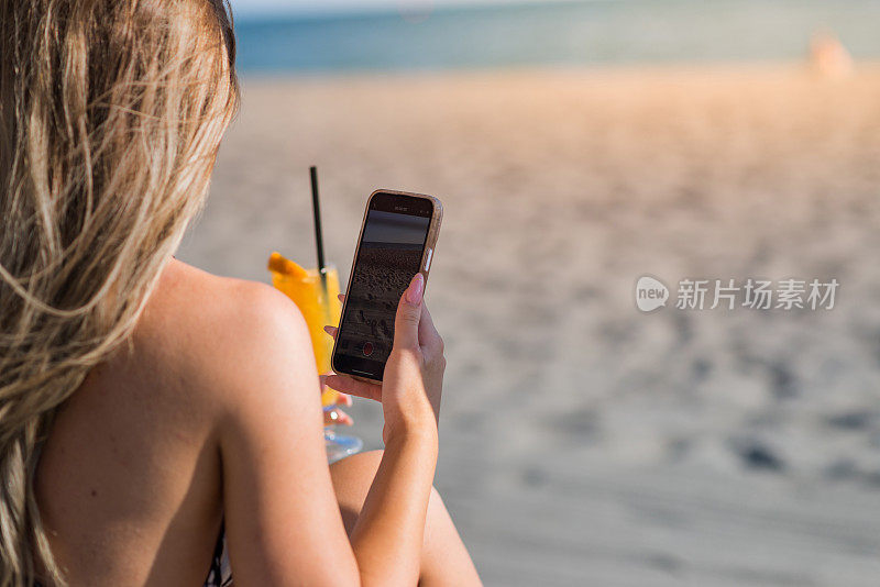年轻女子在热带海滩上喝鸡尾酒，库存照片