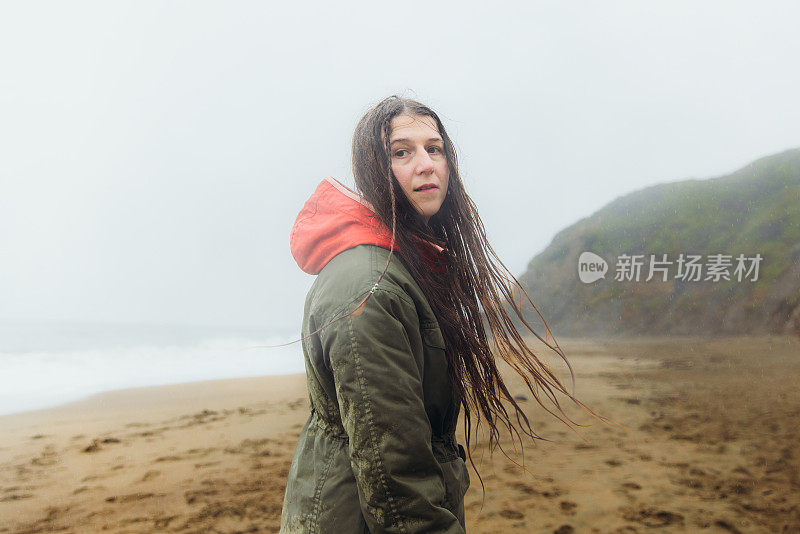 在加利福尼亚旧金山的海滩上散步的女人在思考下雨天