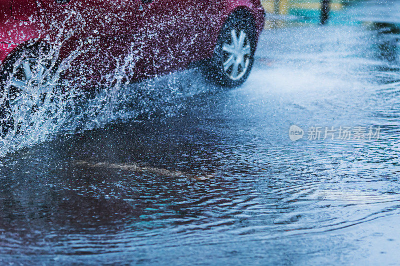 汽车溅起的水花。路上的水坑。多雨的天气。下雨了。