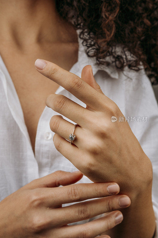 金戒指戴在女性的手上，钻石钻石戒指在年轻女士的手上。特写照片拍摄