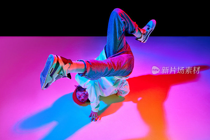 一个30多岁的动感男子，在霓虹灯的黑色工作室背景上跳着霹雳舞