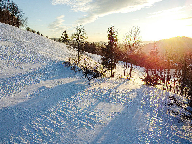 日落时的冬日风景，白雪覆盖的山丘和晴朗的天空