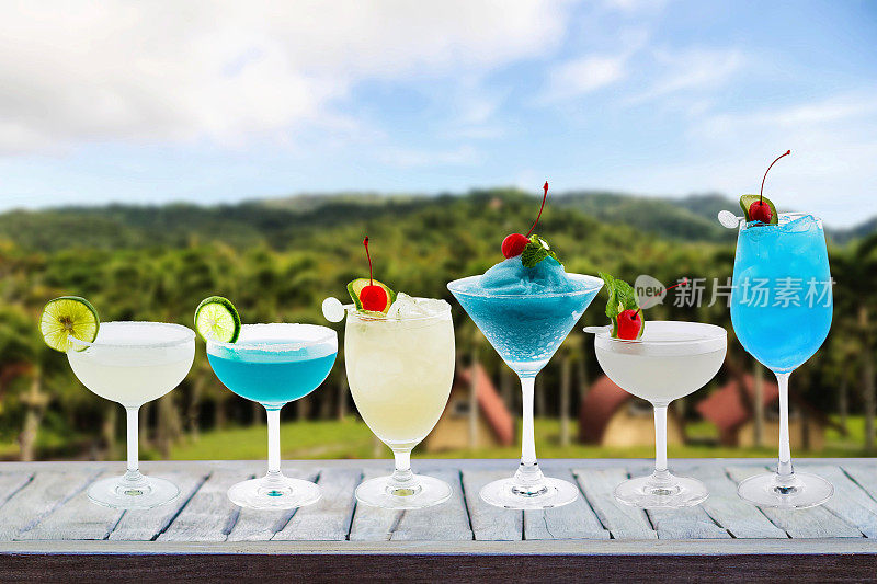 色彩缤纷的夏日鸡尾酒在玻璃杯里，鸡尾酒在木桌和露营自然景观的背景下，假期旅行的想法与节日聚会庆祝成功有酒