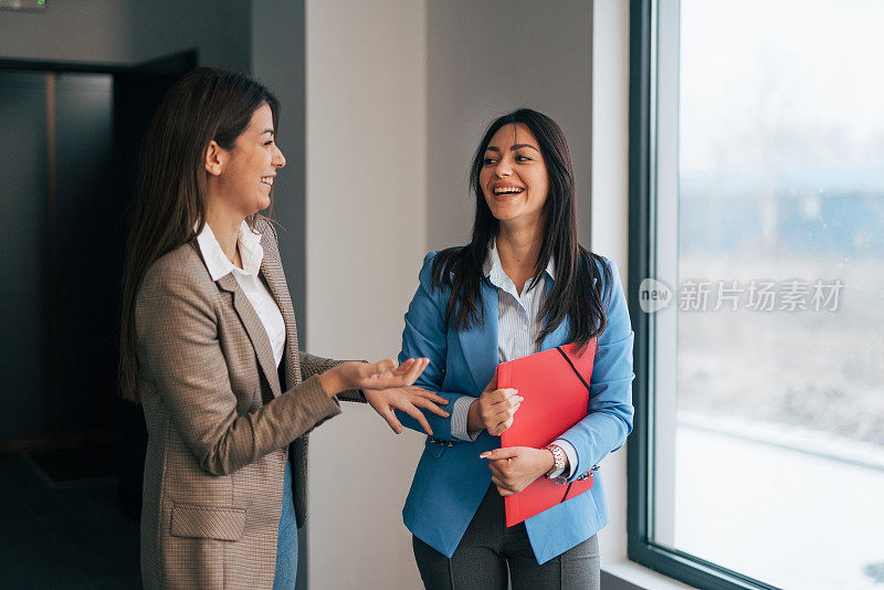 两个年轻的女商人在商业走廊里聊天