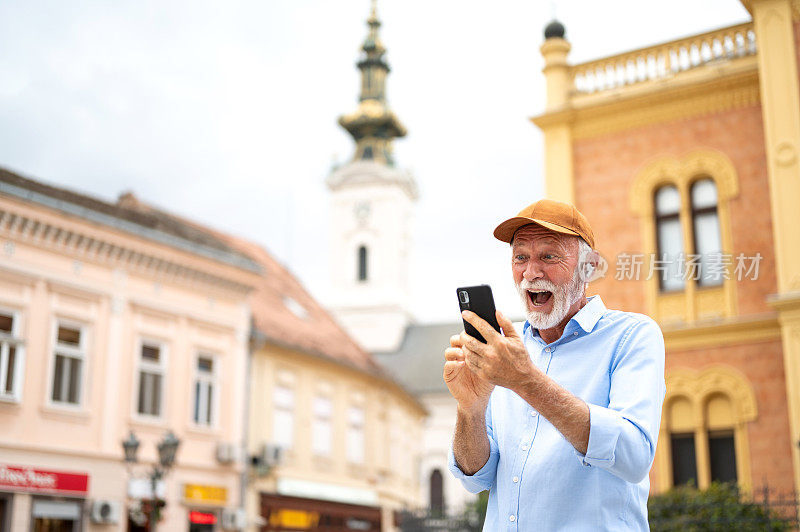 照片中，酷酷的、面带微笑的老年人拿着智能手机欢呼