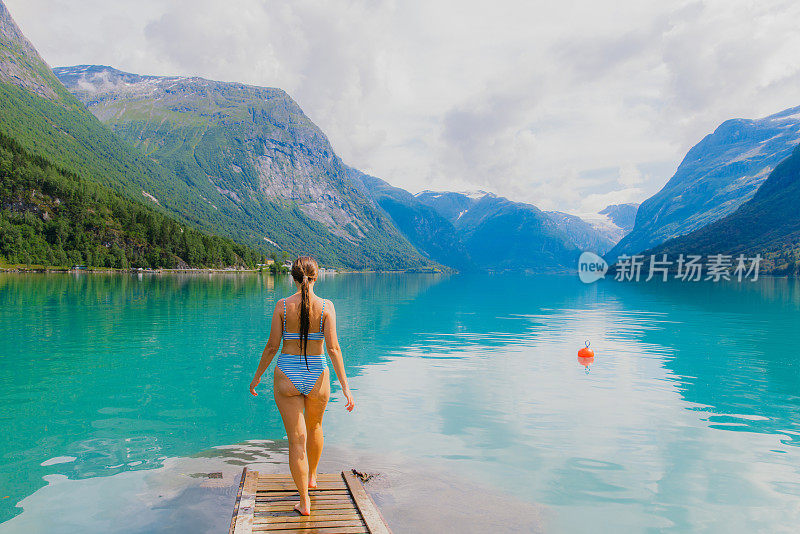 在水晶山湖游泳的快乐女人欣赏挪威的夏天