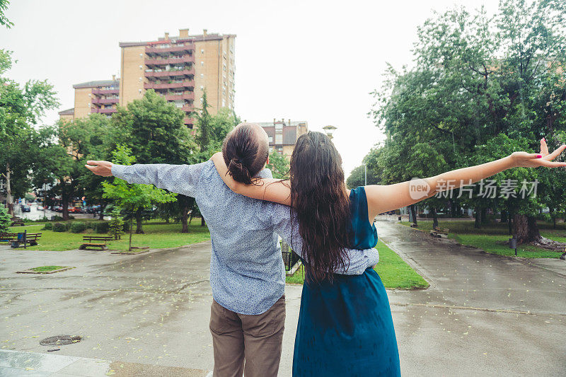 在雨中伸出双臂的情侣